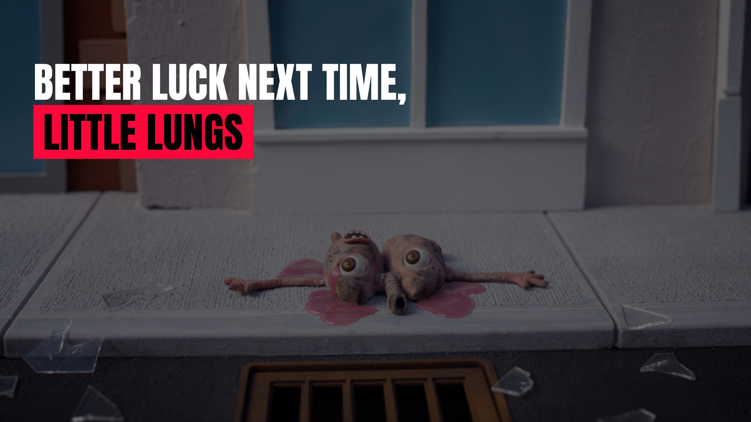 Graphic anti-smoking image showing a pair of cartoonish, damaged lungs lying on a sidewalk near a storm drain, with shattered glass around them. The text reads, “Better luck next time, Little Lungs.”